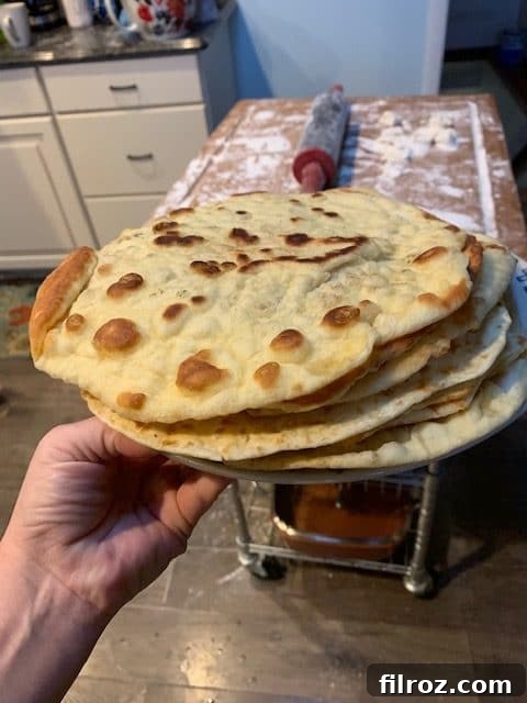 Naan bread cooking on a hot cast iron skillet, bubbling beautifully.