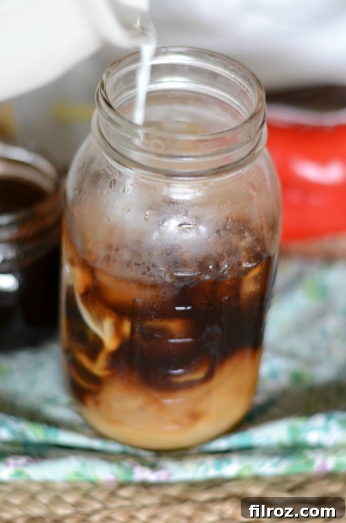 Cream swirling into a glass of spiced cold brew coffee