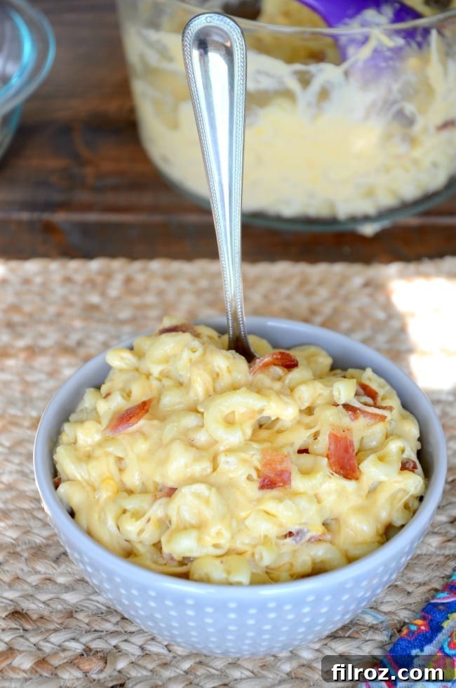 A close-up shot of a bowl of creamy, golden homemade bacon mac and cheese, garnished with fresh parsley.