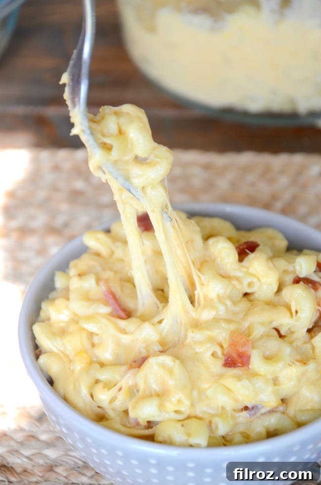 A close-up of bacon strips frying in a skillet, creating aromatic, crispy pieces for the mac and cheese.
