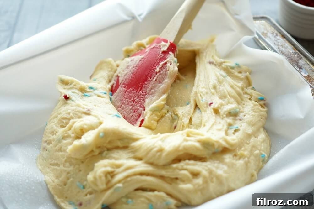 Buttery Sugar Cookie Bars 7 Cookie dough spread evenly in a parchment-lined baking pan