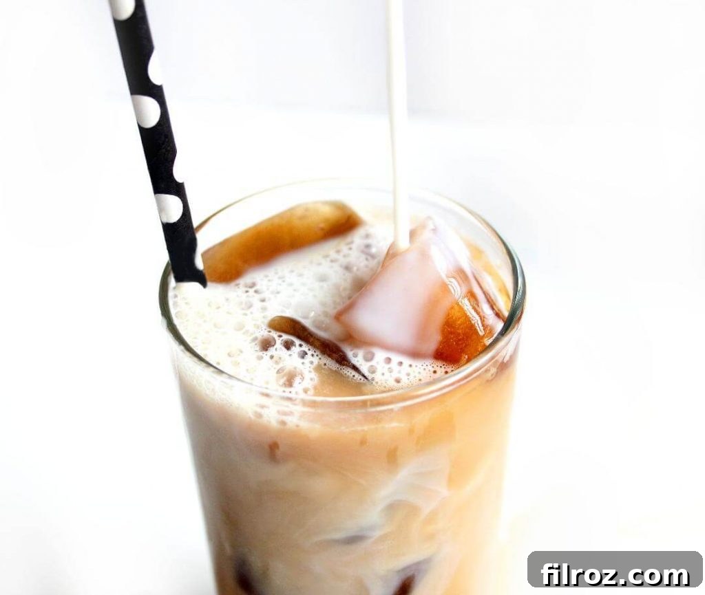 A hand stirring a homemade iced vanilla latte.