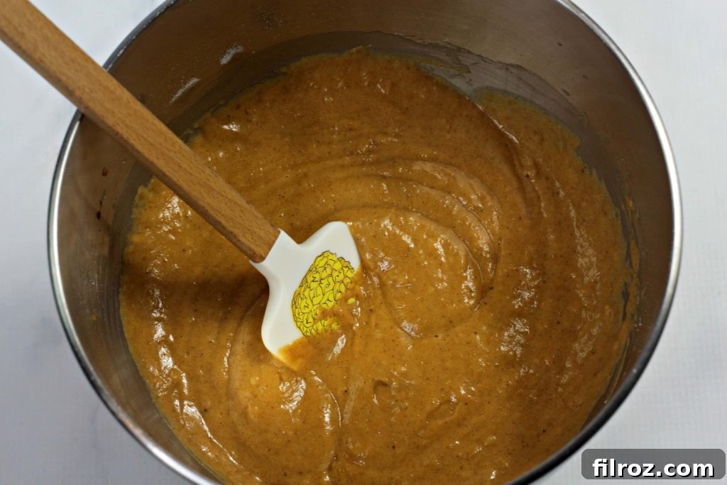 Adding pumpkin puree to the wet batter for an easy pumpkin bread recipe