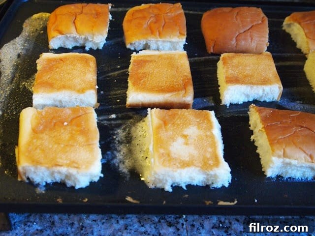 Hawaiian King Sub Rolls sliced and toasting on a buttered griddle.