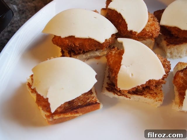Bottom slider buns topped with chicken nuggets and pasta sauce, ready for cheese.