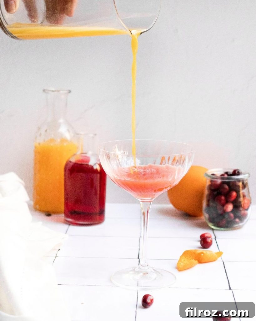 Pouring cranberry juice into orange juice for mimosa