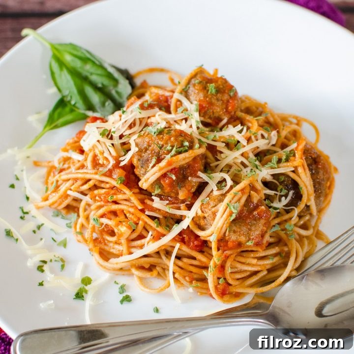 A classic plate of homemade spaghetti and meatballs, garnished with fresh parsley and grated Parmesan cheese.